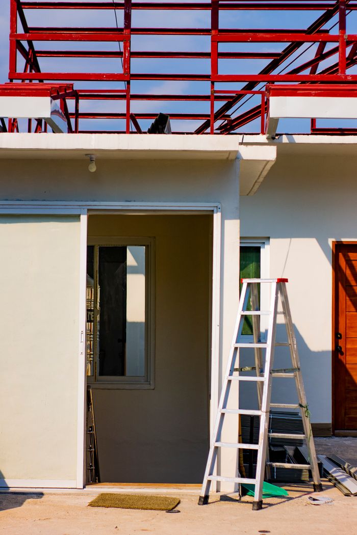 Modern house under renovation with visible scaffolding and ladder.